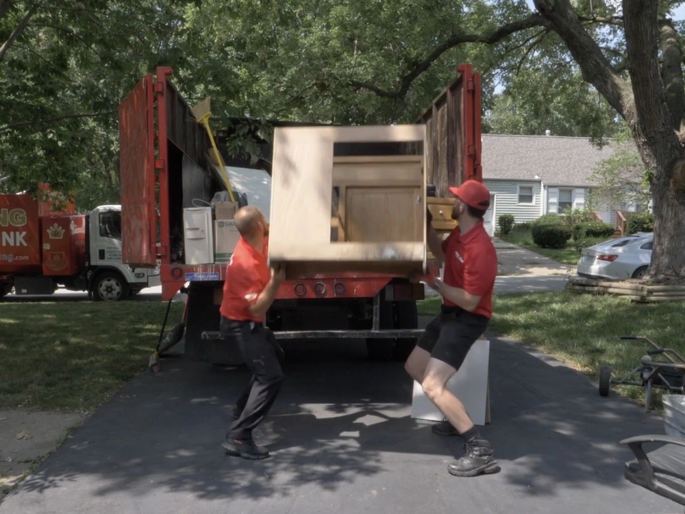 junk-king-team-loading-cabinet-on-driveway removing construction debris in wake forest